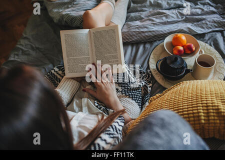 Donna che legge un libro sul letto Foto Stock