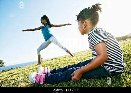 Nero Ragazza guarda la madre a praticare yoga Foto Stock