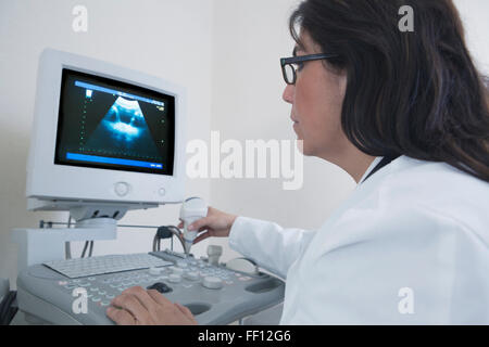 Medico di origine ispanica esaminando sonogram in ospedale Foto Stock