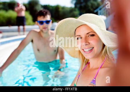 Matura in piscina tenendo selfie. Estate e acqua. Foto Stock