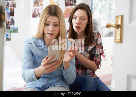 Ragazza con un amico di essere vittima di bullismo mediante messaggio di testo Foto Stock