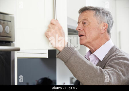 Dimentico Senior uomo cercando in armadio Foto Stock