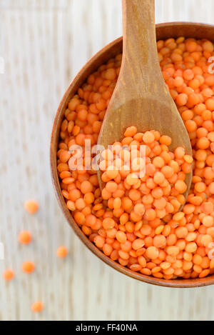 Di lenticchie rosse in cucchiaio su una tavola di legno Foto Stock