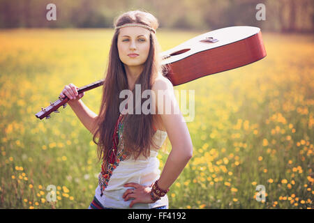 Bella donna hippie con la chitarra in un campo estivo. La pace e l armonia Foto Stock