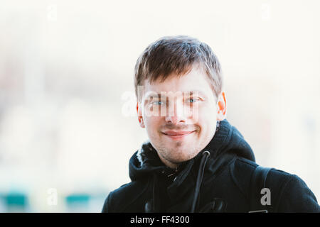 Giovane uomo bello sorridente all'aperto vicino fino street portrait. Foto Stock