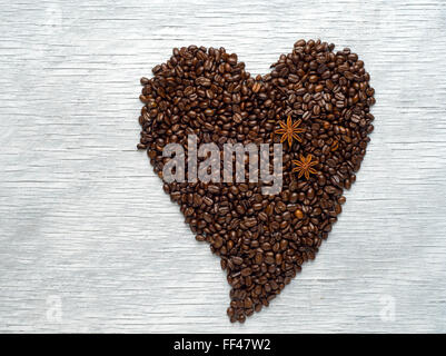 Forma di cuore fatta da chicchi di caffè su sfondo di legno Foto Stock