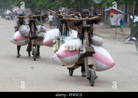 Gli abitanti di un villaggio con prodotti agricoli montati su 'chukudu' in casa di legno in scooter Kiwanja vicino a Rutshuru Nord Kivu, Congo Repubblica Democratica del Congo Foto Stock