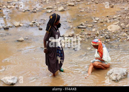 SENBETE, ETIOPIA-marzo 24, 2013: Le donne-oromo chat persone e organi di lavaggio in acqua di fiume che scorre attraverso il mercato. Foto Stock