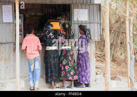 SENBETE, ETIOPIA-marzo 24, 2013: donne locali e ragazzo di comprare qualche olio-tin booth attraverso la strada-mercato di domenica. Oromos-amhara-afar. Foto Stock