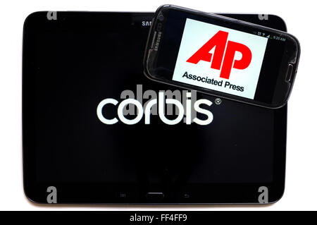 Il logo Corbis su uno smartphone e Associated Press su un tablet fotografati contro uno sfondo bianco. Foto Stock