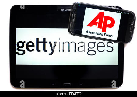 Il logo di AP su uno smartphone e Getty Images su un tablet fotografati contro uno sfondo bianco. Foto Stock