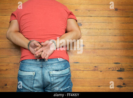Uomo sdraiato sul legno del pavimento sporco con le manette Foto Stock