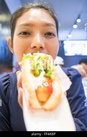 Ritratto di una donna di mangiare un hot dog Foto Stock