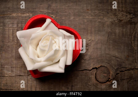 Cuore rosso a forma di scatola regalo con un bianco rosa in plastica Foto Stock