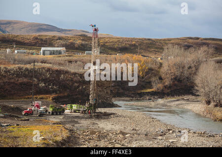 Un olio e gas service rig funziona su un lavato fuori wellsite lungo la riva del fiume Highwood nel sud dell'Alberta pedemontana Foto Stock