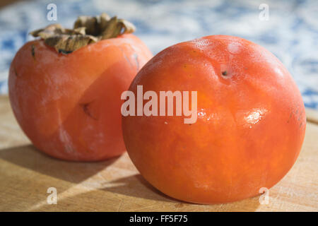 Mature e colorato Cachi freschi organici e sul piatto di legno Foto Stock