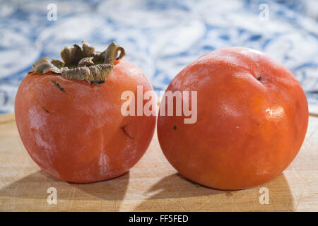 Mature e colorato Cachi freschi organici e sul piatto di legno Foto Stock