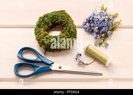 Rendendo omaggio floreale con dimenticare-me-non fiori. Bianco sullo sfondo di legno. Foto Stock