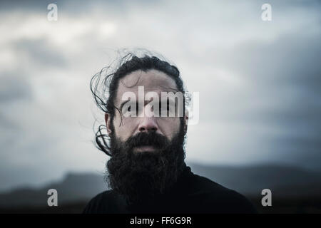 Un uomo con i capelli neri un pieno di barba e baffi. Foto Stock