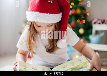 Bella ragazza, la lettura di un libro di fronte all'albero di Natale, dettaglio shot sulle ciglia Foto Stock