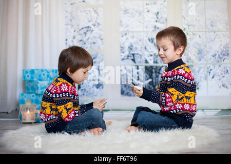 Due adorabili bambini, ragazzo fratelli, giocando a carte a casa, inverno, la decorazione di Natale intorno a loro, snowy giorno dietro il w Foto Stock