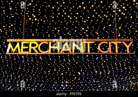 Il Merchant City sign in Royal Exchange Square, Glasgow city centre, illuminata di notte contro un sfondo scintillanti. Foto Stock