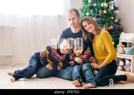 La famiglia felice avendo divertimento a casa natale ritratto di famiglia nella parte anteriore dell'albero di Natale Foto Stock