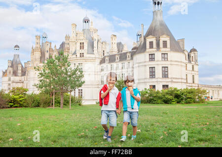 Due ragazzi adorabili in abbigliamento casual, mangiare il gelato seduto su un prato di fronte al più grande castello lungo il fiume Loira, C Foto Stock