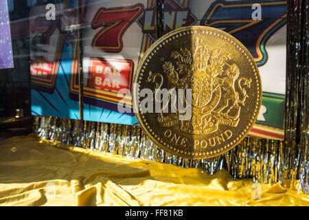 Un modello di grandi dimensioni di un British una libbra di moneta nella finestra di visualizzazione di una Cashino divertimento arcade a Lewisham, Londra, Regno Unito. Foto Stock