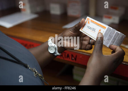 Un infermiere tenendo un pacchetto di medicazione Travisil in una medicina ripostiglio, Tanzania. Foto Stock