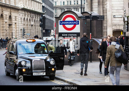 Un passeggero britannico ottiene in un taxi nero al di fuori della cabina Stazione della metropolitana di Bank nel centro di Londra, Regno Unito. Il famoso per le tradizionali taxi neri sono un'immagine iconica di Londra e può essere prenotato in anticipo o salutato sulle strade o indicate da file di taxi. I taxi nome ufficiale è Hackney carrello. Foto Stock