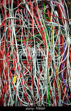 Una grande massa di multi-colore dei cavi del computer in una sala server in un British business office di Londra, Regno Unito. Foto Stock