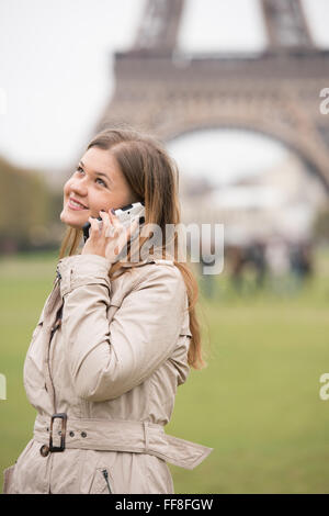 Giovane donna graziosa in piedi di fronte a torre eifel, Parigi, Francia, parlando al telefono cellulare Foto Stock