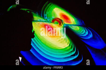 La silhouette di uno scienziato contro una visualizzazione delle onde gravitazionali illustrato nel corso di una conferenza stampa dall'Istituto Max Planck per la Fisica della Gravitazione (Albert Einstein Institute) presso l'Università Leibniz di Hannover, Germania, 11 febbraio 2016. Spazio i ricercatori dicono di avere direttamente provate l esistenza delle onde gravitazionali per la prima volta. L'astrofisici dall'Osservatorio Ligo negli Stati Uniti hanno presentato la loro scoperta a Washington. Scienziati provenienti dalla Germania sono anche stati coinvolti nel progetto. Foto: JULIAN STRATENSCHULTE/DPA Foto Stock