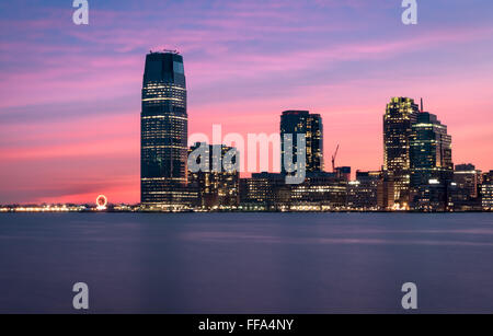Un bellissimo tramonto sui grattacieli di Paulus Hook Jersey City e il fiume Hudson, con un cielo rosa riflessa nell'acqua. Foto Stock