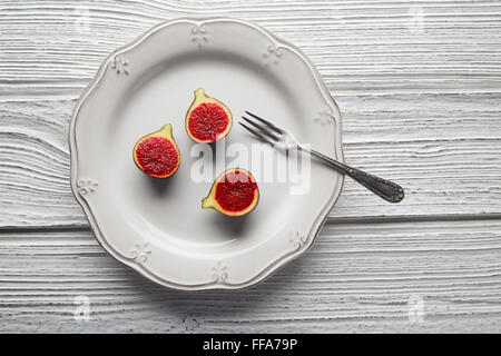 Le figure intagliate greggio fig frutti sulla piastra bianca e tavolo in legno