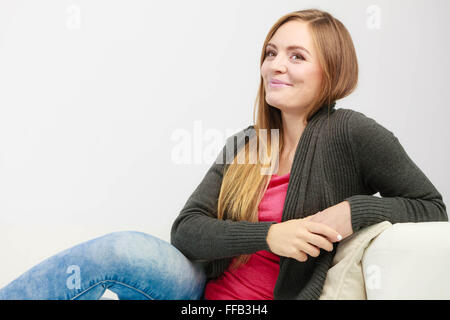 Molto felice e soddisfatto femmina. Bella marrone lungo la donna dai capelli rilassante sul lettino a casa Foto Stock