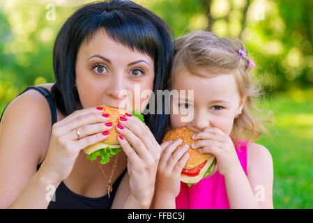 Ritratto della madre con la figlia nel parco con hamburger Foto Stock