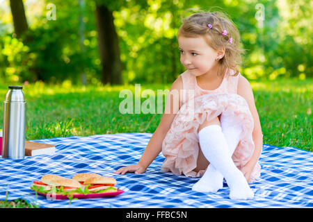 Bellissima bambina di 6 anni seduto sul plaid nel parco Foto Stock