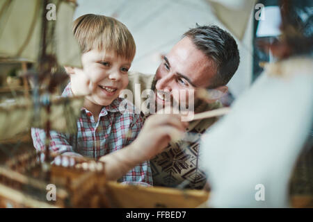 Ragazzo simpatico giocattolo di pittura nave con suo padre nelle vicinanze Foto Stock