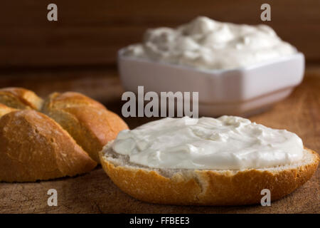 Organico sano grano intero bagel con formaggio spalmabile su sfondo di legno Foto Stock