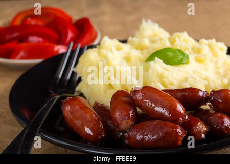 Salsicce e purè di patate con sottaceti in background Foto Stock