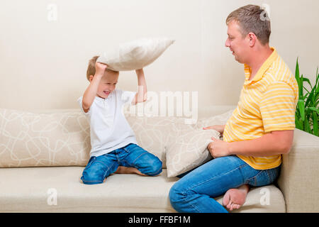 Padre e figlio combattendo i cuscini sul lettino Foto Stock