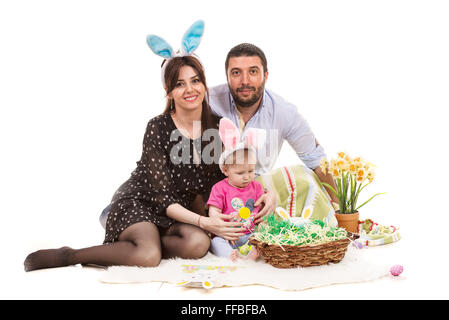 Felice madre, padre e figlia del bambino seduto su una coperta con decorazioni di Pasqua Foto Stock