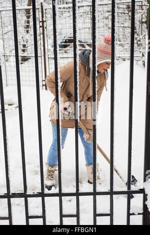 Donna di lavoro con la Pala da neve da recinzione Foto Stock