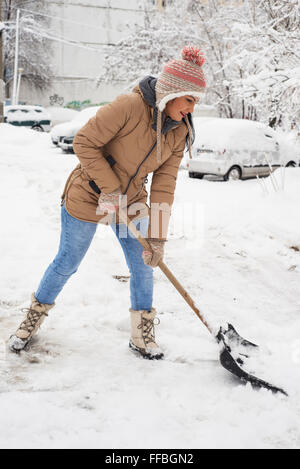 Donna di pulizia nella neve il parcheggio nel freddo giorno Foto Stock