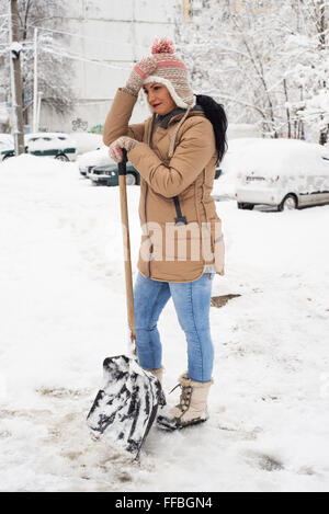 Donna di lavoro con la Pala da neve per prendersi una pausa Foto Stock