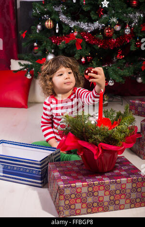 Il Toddler boy sotto albero di Natale regali di apertura e giocare con le palle Foto Stock