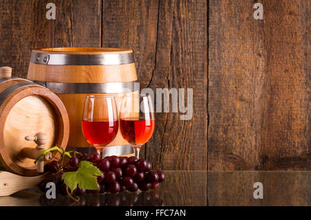 Bicchieri di vino rosato con due canne uve e scuro dello sfondo in legno Foto Stock