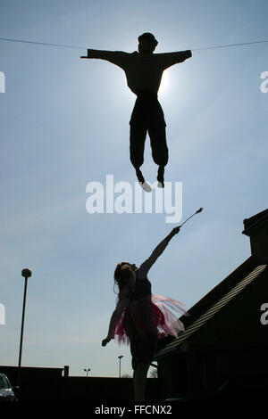 Tra le case di un ebreo street in Stamford Hill la figura di Haman inssuspended nel cielo durante la festa di Purim. Una giovane ragazza vestita come una fata per la festa di Purim, prova a battere su di esso con la sua bacchetta magica. Purim è uno dei più divertenti vacanze ebraiche. Essa commemora il tempo quando il popolo ebraico vive in Persia furono salvati dallo sterminio da un massacro da Haman. Grazie al coraggio di una giovane donna ebrea chiamato Ester si è soliti tenere il carnevale-come celebrazioni. Foto Stock